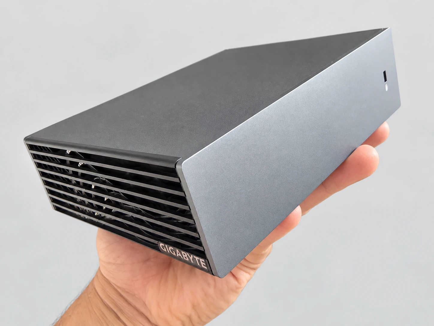 Die AI TOP ATOM in einer Hand, in Dreiviertelansicht: Das Gehäuse ragt kaum über die Handfläche hinaus.