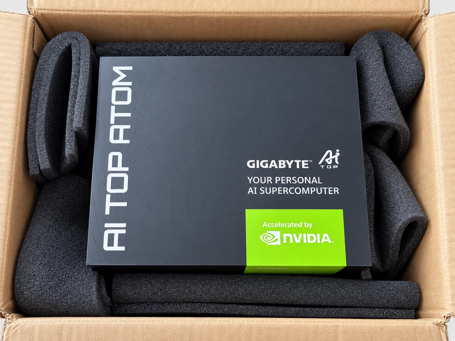 Schwarze Box des AI TOP ATOM in ihrem Versandkarton, mit Schaumstoff fixiert, mit den Aufschriften GIGABYTE AI TOP und Accelerated by NVIDIA.
