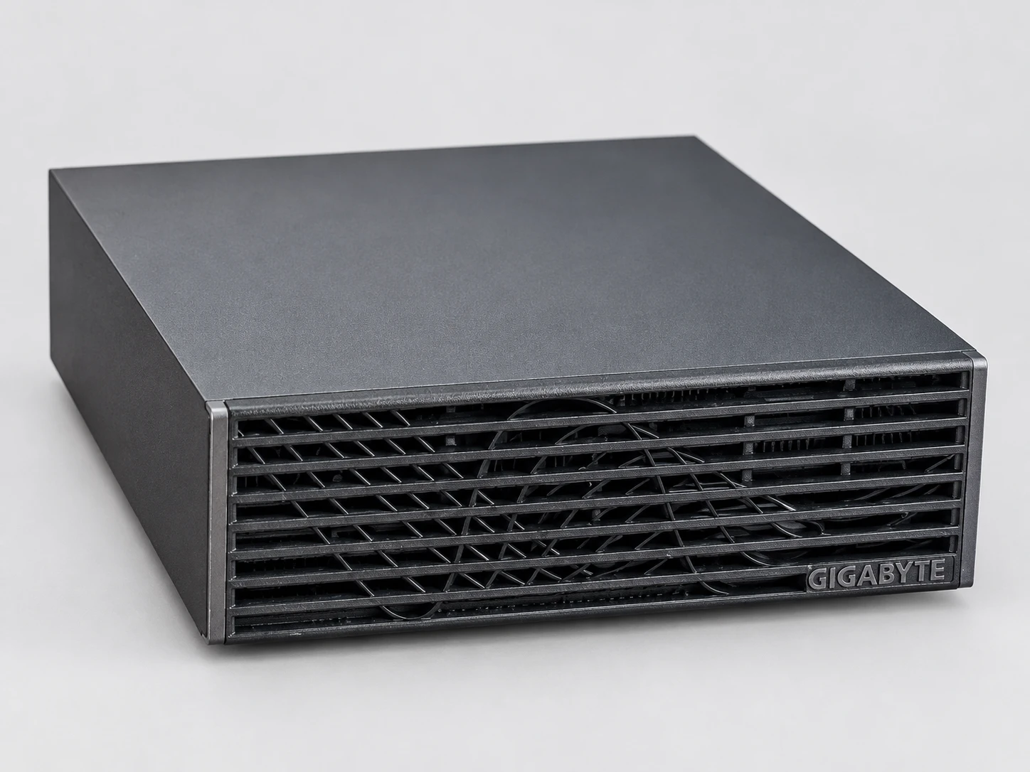 Der GIGABYTE AI TOP ATOM von schräg rechts gesehen, flach aufliegend: anthrazitgraue Abdeckung und schwarze Lamellen an der Vorderseite.