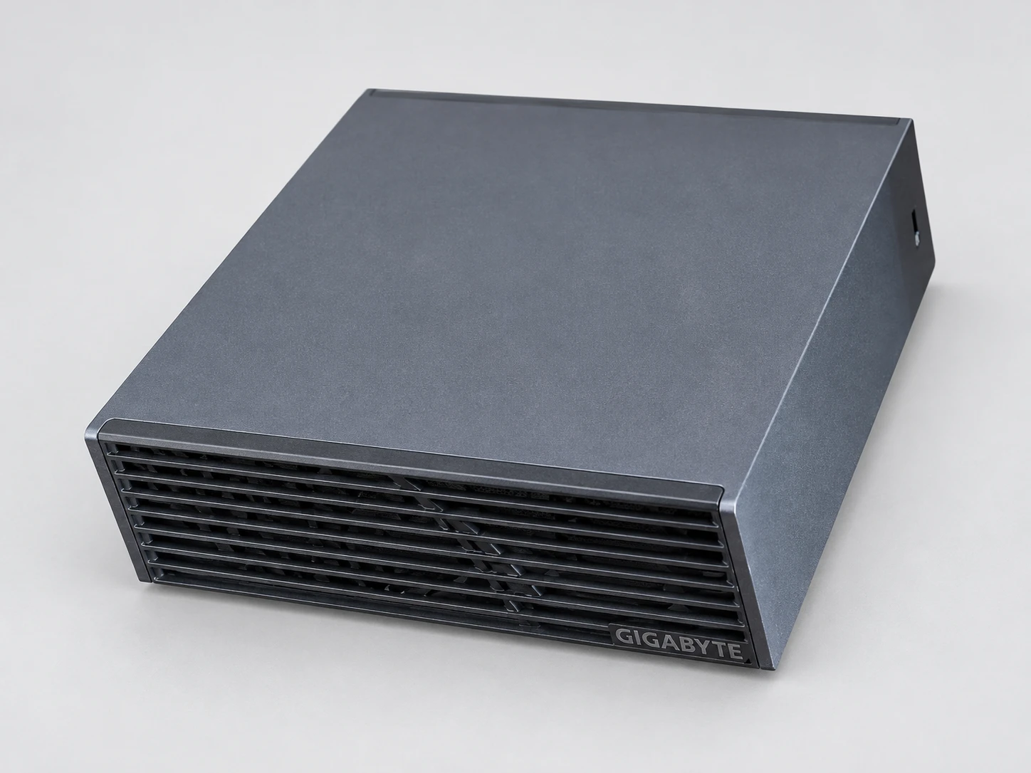 Die AI TOP ATOM von GIGABYTE in Dreiviertelansicht: anthrazitgraues Gehäuse, schlichter Deckel, Front mit horizontalen Lamellen und GIGABYTE-Logo.